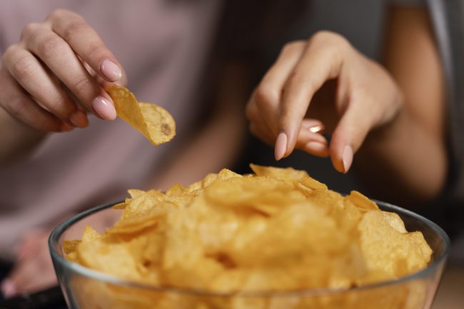women-on-couch-watching-tv-and-eating-chips-close-up