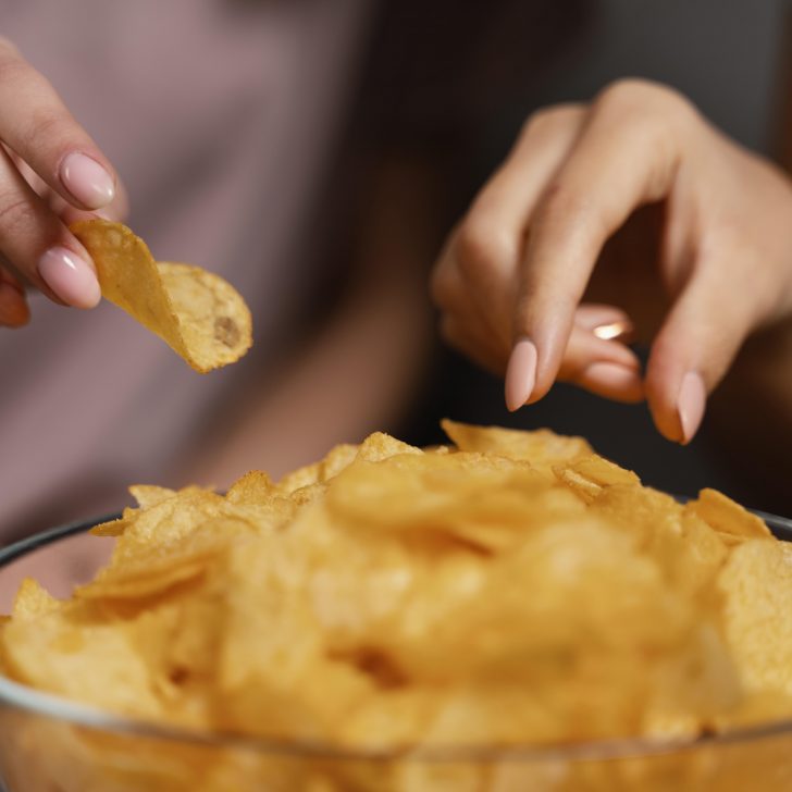 women-on-couch-watching-tv-and-eating-chips-close-up