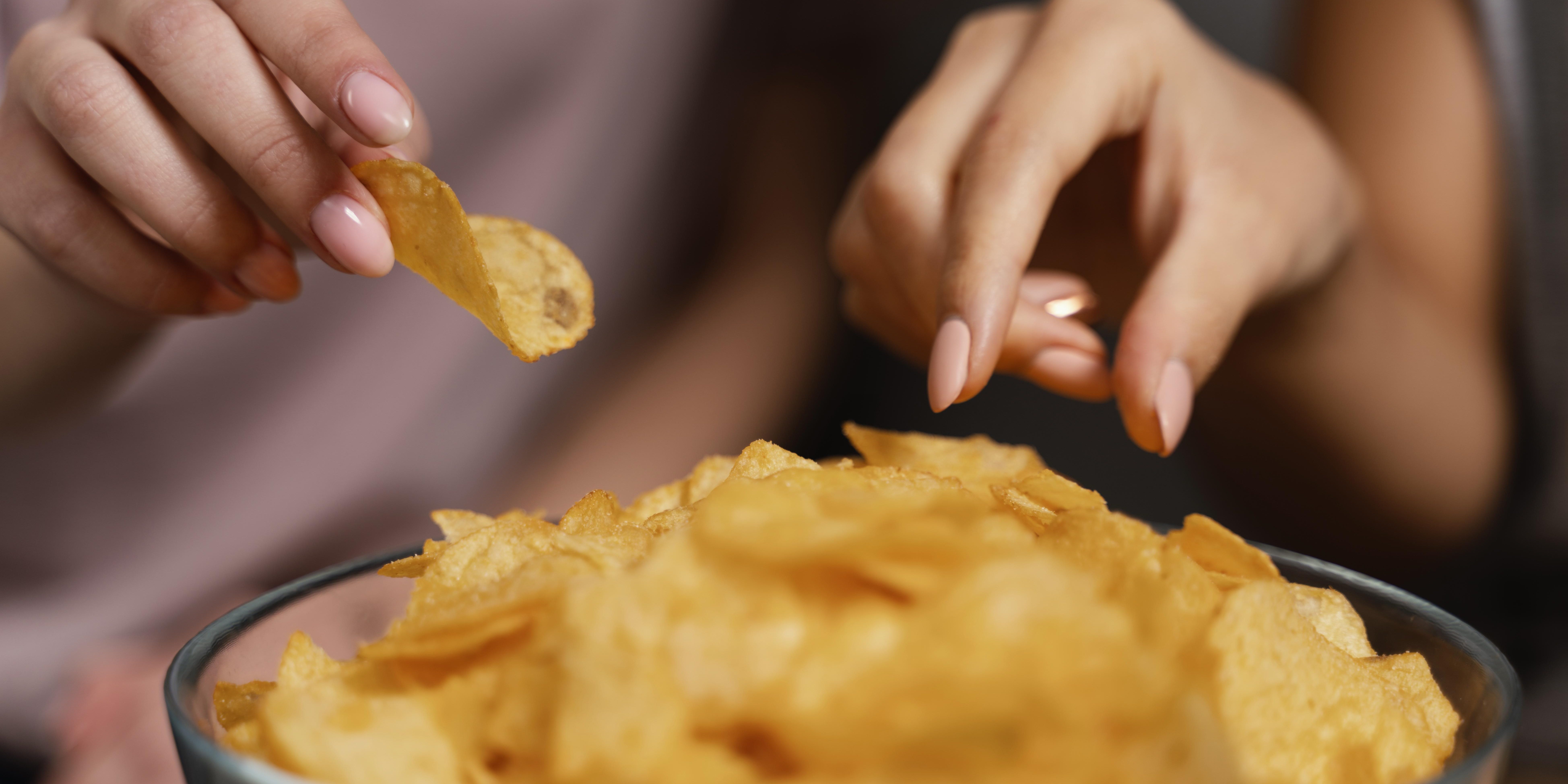 women-on-couch-watching-tv-and-eating-chips-close-up